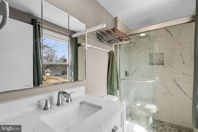 bathroom with toilet, a marble finish shower, and vanity