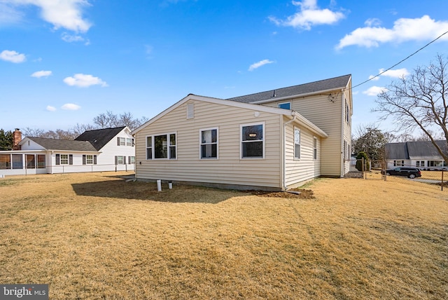 rear view of house with a yard and fence