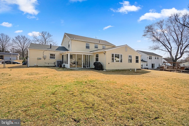 back of house featuring a sunroom, fence, and a lawn