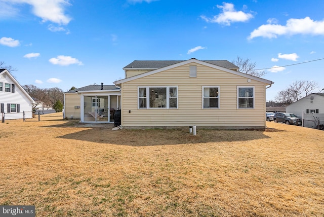 rear view of house featuring a yard and fence