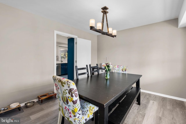 dining room featuring a chandelier, baseboards, and wood finished floors