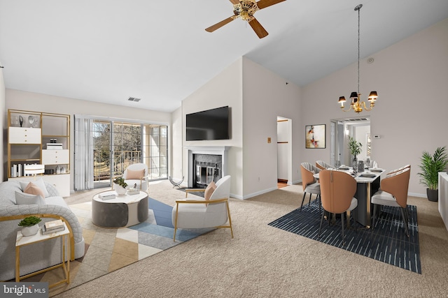 living area featuring high vaulted ceiling, light carpet, visible vents, baseboards, and a glass covered fireplace