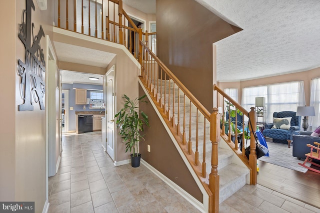 stairs featuring a textured ceiling, tile patterned floors, and baseboards