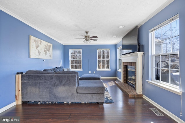 living area featuring hardwood / wood-style flooring, baseboards, a fireplace, and visible vents