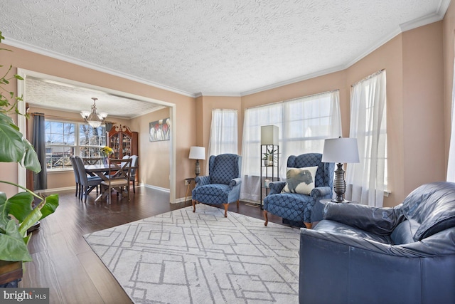 living room featuring a chandelier, ornamental molding, wood finished floors, and baseboards