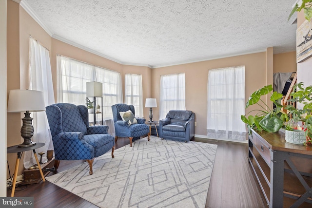 sitting room featuring a textured ceiling, ornamental molding, plenty of natural light, and wood finished floors