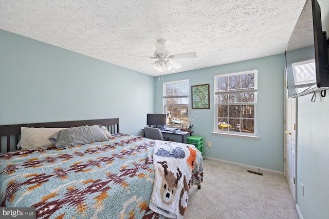 carpeted bedroom with a ceiling fan, a textured ceiling, and baseboards