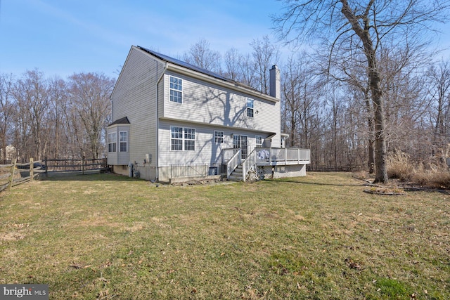 back of house featuring a yard, a chimney, fence, and a wooden deck