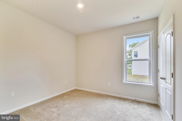 spare room featuring visible vents, light carpet, and baseboards