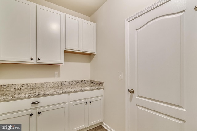 interior space with light stone counters, white cabinets, and baseboards