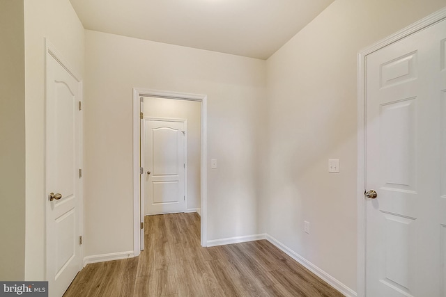 hallway featuring light wood finished floors and baseboards