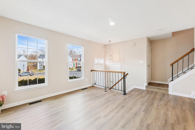 unfurnished room featuring visible vents, light wood-style flooring, and baseboards