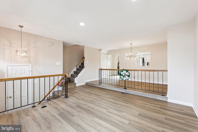 empty room featuring a chandelier, recessed lighting, baseboards, and wood finished floors