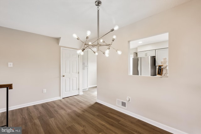 unfurnished dining area with an inviting chandelier, baseboards, visible vents, and dark wood-type flooring