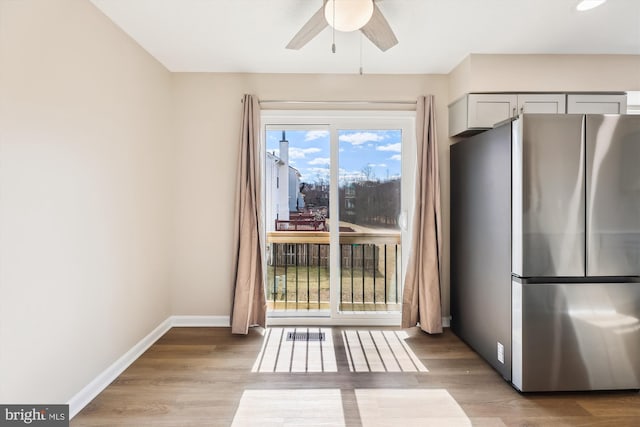 unfurnished dining area with light wood-style floors, ceiling fan, and baseboards