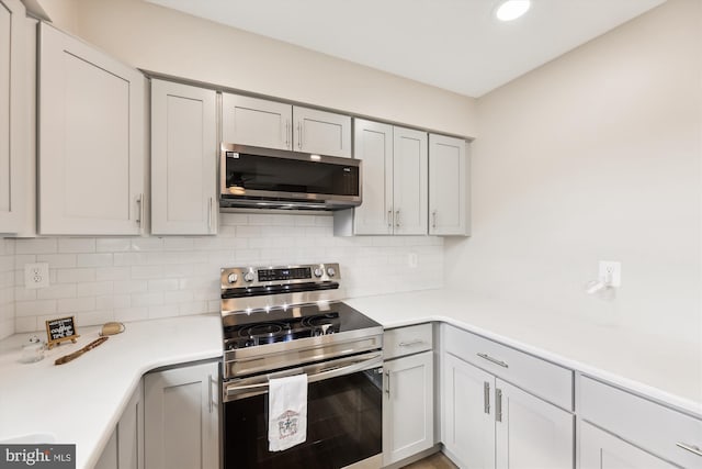 kitchen with gray cabinets, appliances with stainless steel finishes, light countertops, and backsplash