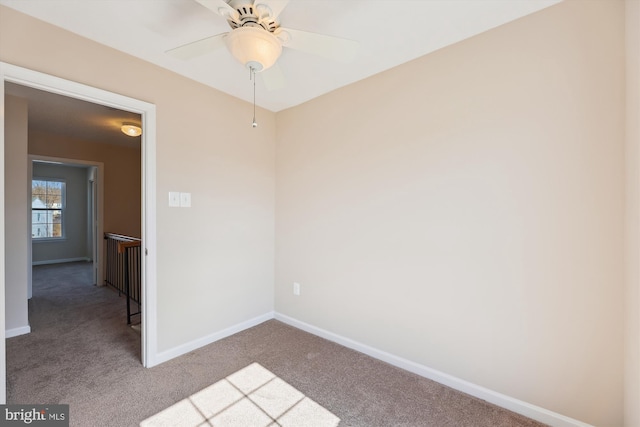 carpeted empty room featuring a ceiling fan and baseboards