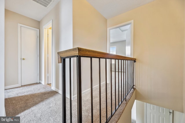 corridor with carpet, attic access, visible vents, and baseboards