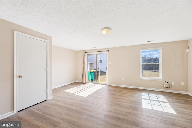 unfurnished room featuring a textured ceiling, baseboards, and wood finished floors