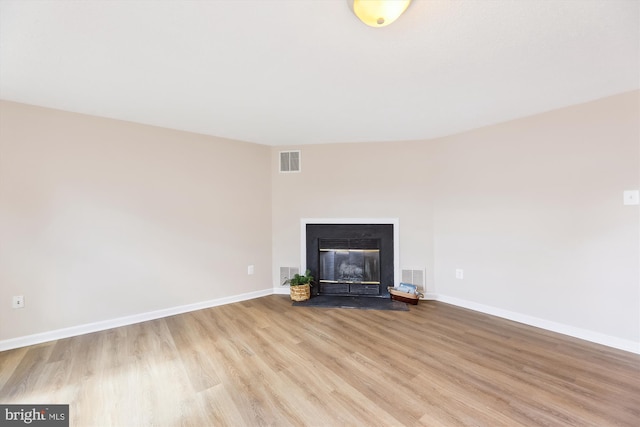 unfurnished living room with wood finished floors, visible vents, and baseboards