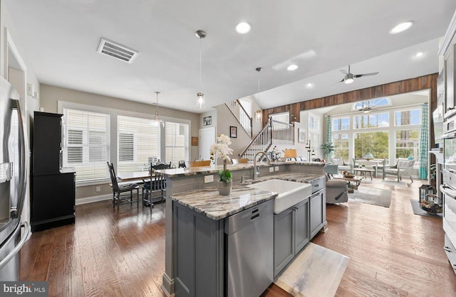 kitchen with visible vents, gray cabinetry, a sink, dark wood-type flooring, and appliances with stainless steel finishes