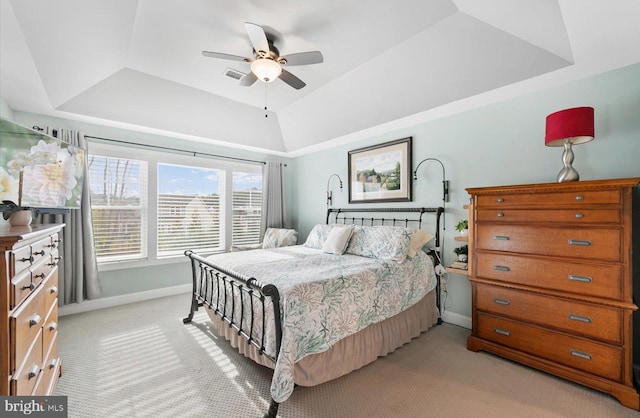 bedroom featuring a ceiling fan, a raised ceiling, light colored carpet, and baseboards