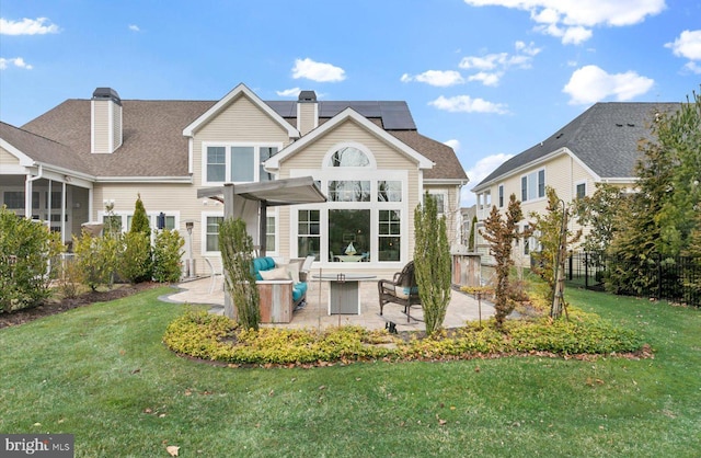 rear view of property with a yard, fence, solar panels, and a patio area