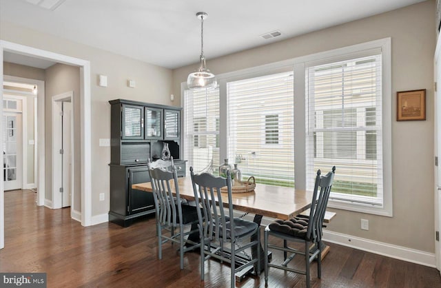 dining space with dark wood-style floors, visible vents, and baseboards