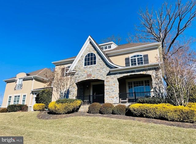 view of front of property featuring stone siding, a front yard, and stucco siding