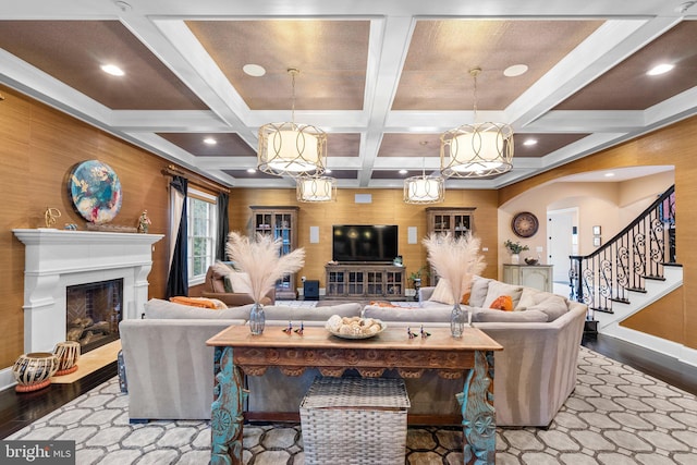 living room featuring beam ceiling, a fireplace, stairway, and wood finished floors