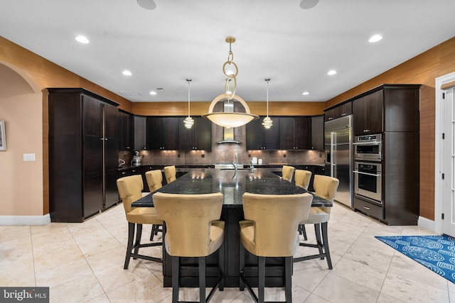 kitchen with appliances with stainless steel finishes, arched walkways, a breakfast bar, and decorative backsplash