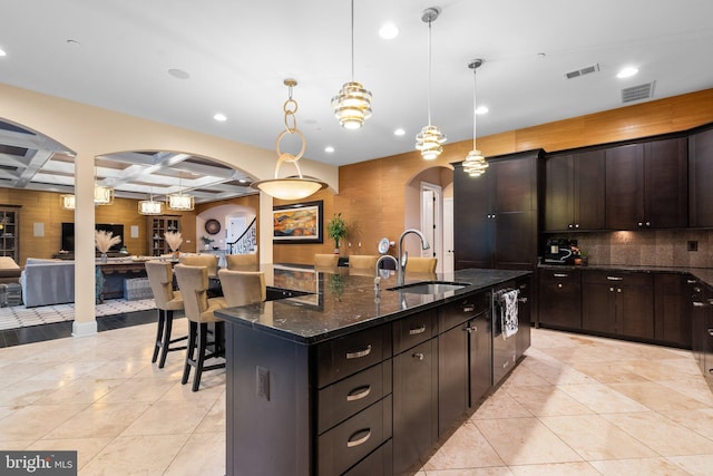 kitchen with arched walkways, decorative backsplash, open floor plan, a sink, and coffered ceiling