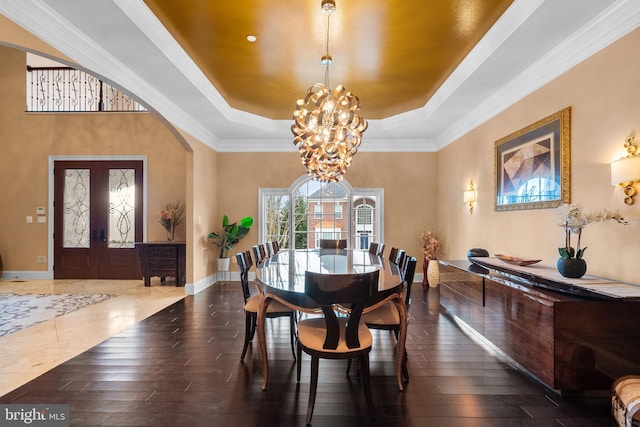 dining area featuring arched walkways, a raised ceiling, hardwood / wood-style floors, and a chandelier