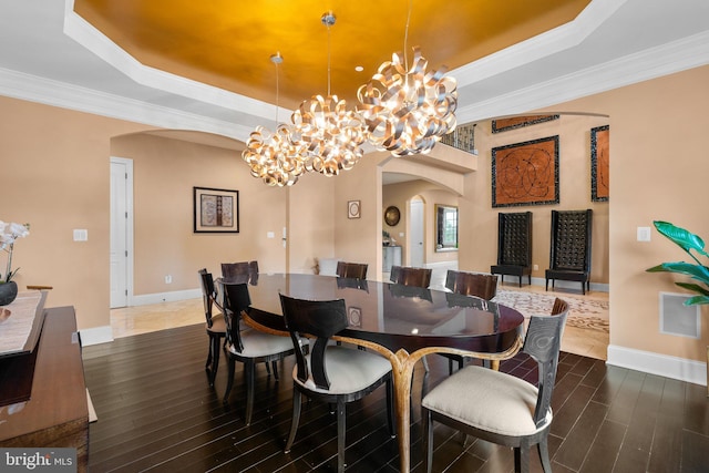 dining room featuring arched walkways, a tray ceiling, dark wood-style floors, and an inviting chandelier