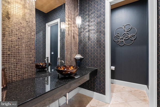 bathroom with wallpapered walls, baseboards, a sink, and tile patterned floors