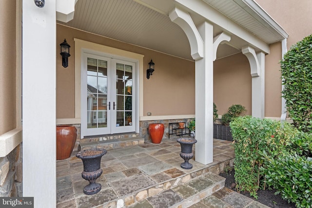 view of exterior entry with stone siding, french doors, and stucco siding