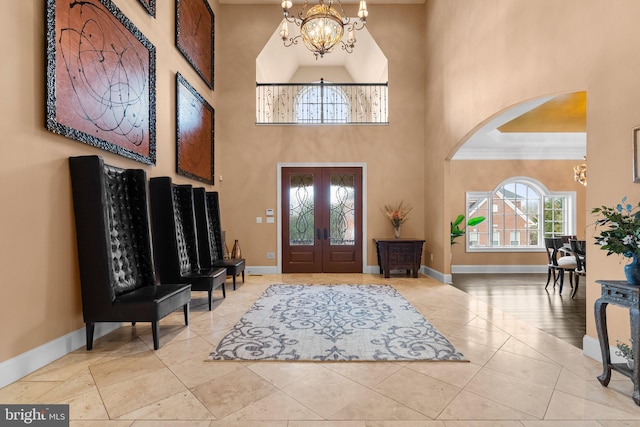 tiled foyer entrance with crown molding, a high ceiling, a notable chandelier, and baseboards