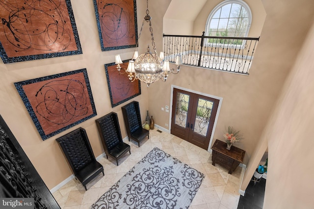 foyer with a high ceiling, baseboards, a chandelier, and french doors