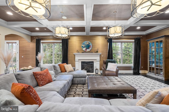 living area with a glass covered fireplace, beam ceiling, coffered ceiling, and wooden walls