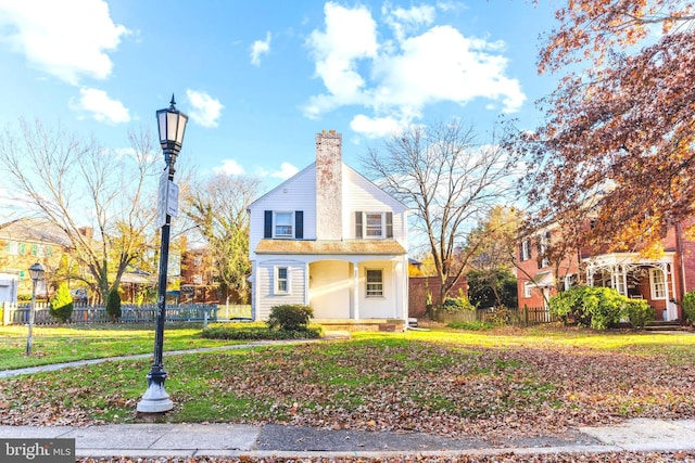 view of front of house with fence, a chimney, and a front lawn