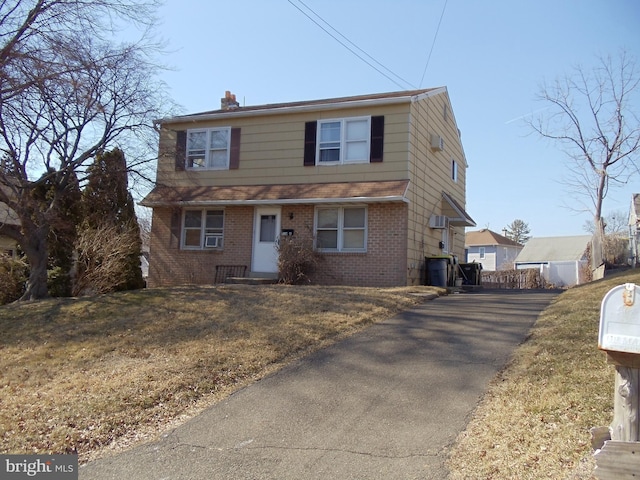 view of front of property featuring brick siding, a chimney, and a front yard