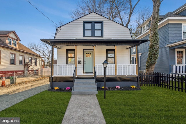 view of front of property with covered porch, fence, and a front lawn