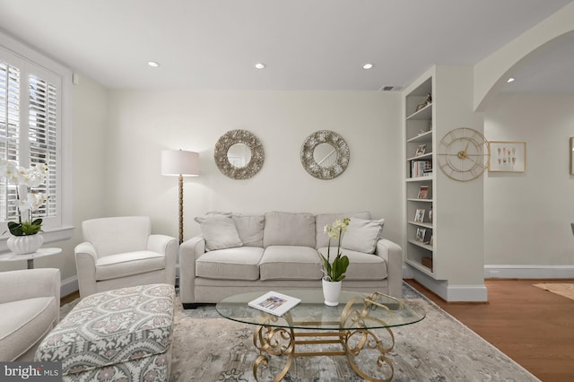 living room with recessed lighting, visible vents, baseboards, and wood finished floors