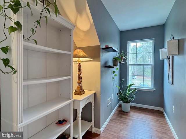 doorway to outside featuring baseboards and wood finished floors