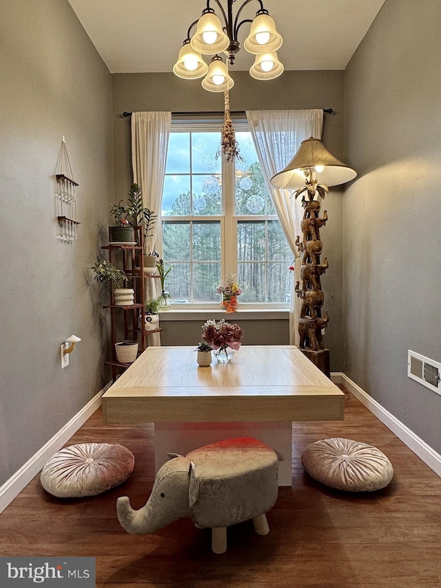 dining room featuring visible vents, baseboards, a notable chandelier, and wood finished floors