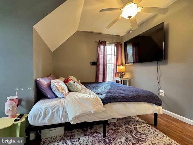 bedroom featuring baseboards, lofted ceiling, wood finished floors, and a ceiling fan