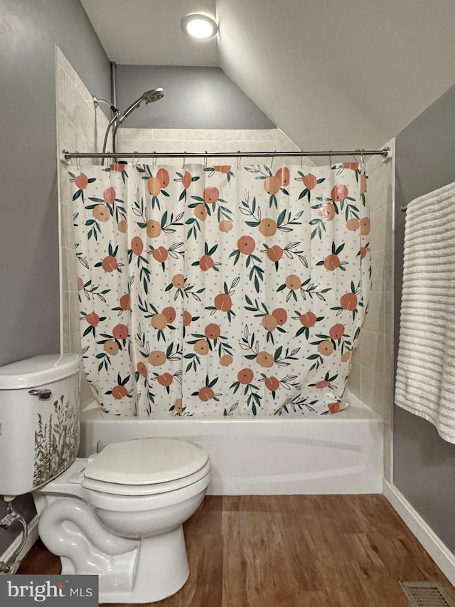 bathroom featuring visible vents, toilet, wood finished floors, and shower / bath combo with shower curtain