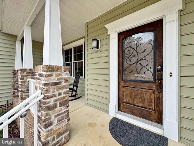 doorway to property featuring brick siding and a porch