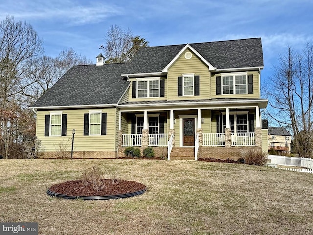 view of front facade with a front lawn, a chimney, covered porch, and a shingled roof