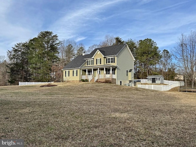 exterior space featuring an outdoor structure, fence, covered porch, and a front lawn